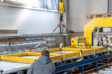 Warehousing of finished products. Conveyor belt or line with packaged metal roof tiles inside workshop using crane. Industrial production of roofing on automated equipment.