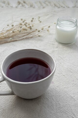 Obraz na płótnie Canvas Nahaufnahme von einer Tasse Tee, eine Kerze und Trockenblumen auf einem beigen Leinen Tischtuch. Frühstück.