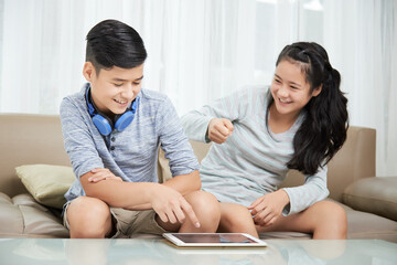 Teenage brother and sister fighting when deciding what to watch on tablet computer