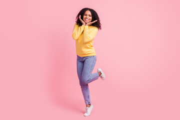 Fototapeta na wymiar Photo of pretty sweet dark skin girl dressed yellow pullover walking arms cheeks smiling isolated pink color background