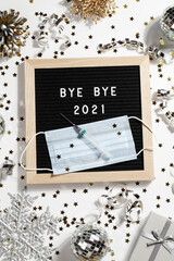 Fototapeta na wymiar black letter board with text BYE BYE 2021 with decoration, syringe and mask on white background.