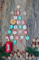 Burning candle on wooden background with 1st advent and homemade decorated gingerbread and fir...