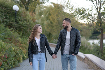 Attractive and stylish guy and girl dressed in autumn casual style are walking in the autumn park.