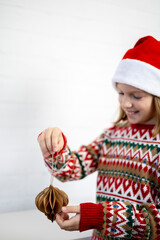 Girl in a knitted Christmas sweater is holding a decoration. DIY origami.