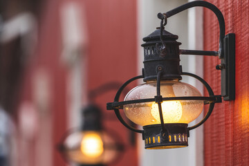 An old lamp on a red wooden facade