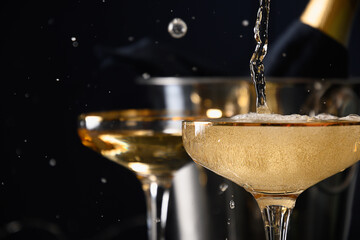 Pouring champagne to wine glasses on black background. 2022 New Year party. Close up. Festive holiday and celebration.