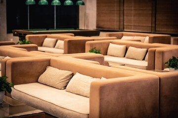 Many light brown yellow velour sofas pillows, billiard table. Modern style Hotel Night club cafe restaurant Hall interior. Comfort peace wealth luxury mood background. Meeting friends good time