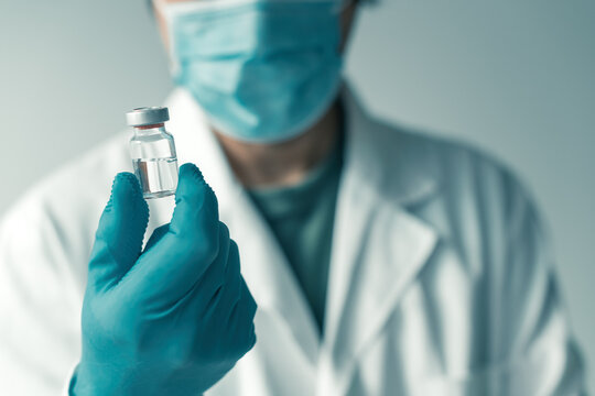 Medical professional holding booster shot Covid-19 vaccine bottle vial