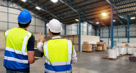 Rear view architect or engineering man and worker standing and checking large warehouse with computer. Multiethnic two business manager looking in future with warehouse building.