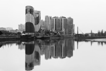 Fototapeta na wymiar view of new modern multi-storey apartment buildings with reflection in the water of the Kuban river on a foggy autumn morning black and white photo