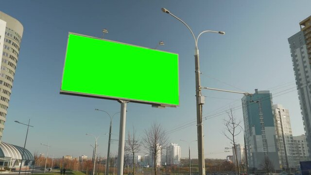 Large billboard in metal frame with blank green space with chromakey for mockup ad information outdoor at city street at autumn day