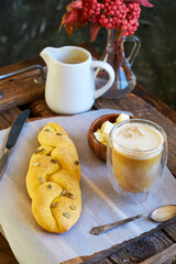 Pumpkin bun with pumpkin seeds and walnuts. Pumpkin latte, walnuts, rowan branch, wooden background, side view.