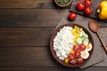 Delicious cottage cheese with vegetables and boiled egg served on wooden table, flat lay. Space for text
