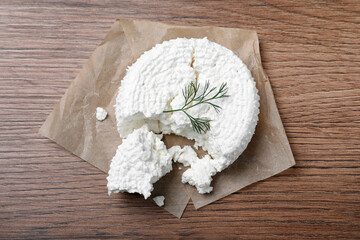 Delicious cottage cheese with dill on wooden table, top view