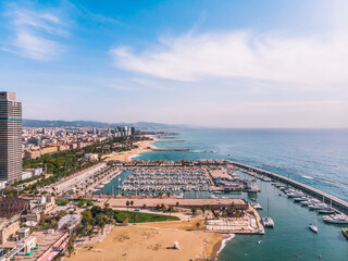 Obraz premium Drone shot Barcelona. Port with boats near the coast. Drone view of a vibrant swimming and sunbathing beach in Barcelona. People are relaxing on the beach. Panoramic view of the city of Barcelona. 