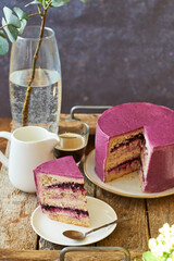 Blueberry purple cake on a wooden stand on a wooden background. Side view, Cake cut