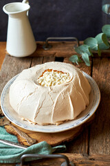 Pavlova cake on a white plate and a wooden board. 