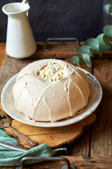 Pavlova cake on a white plate and a wooden board. 