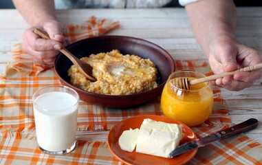 Delicious homemade pumpkin porridge on wooden background. Elderly woman's hands over food. Healthy...