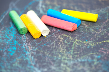 Colored chalk on a dark school board. The concept of children's creativity games, back to school. Blackboard with multicolored strokes from the chalk. Background texture with place for text, flat lay.