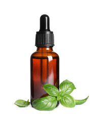 Glass bottle of basil essential oil and leaves on white background