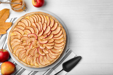 Flat lay composition with tasty apple pie on white wooden table, space for text