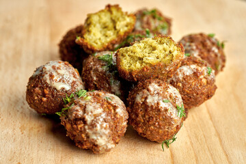 A traditional oriental dish is chickpea falafel with white sauce on a wooden board. Close-up, selective focus