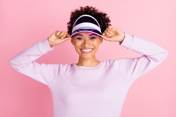 Portrait of young good looking smiling afro american sportive woman training wear visor isolated on pink color background