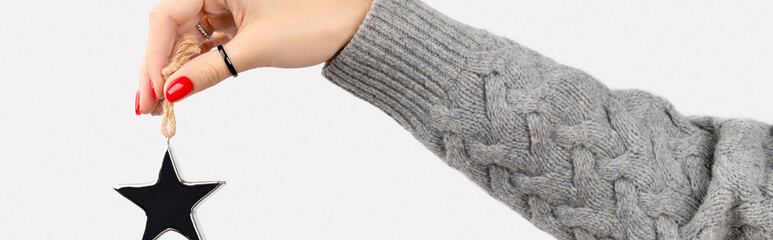 Hand with manicure holding star ornaments on gray background