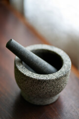 Vertical shot of a stone mortar with pestle on a wooden surface - obrazy, fototapety, plakaty
