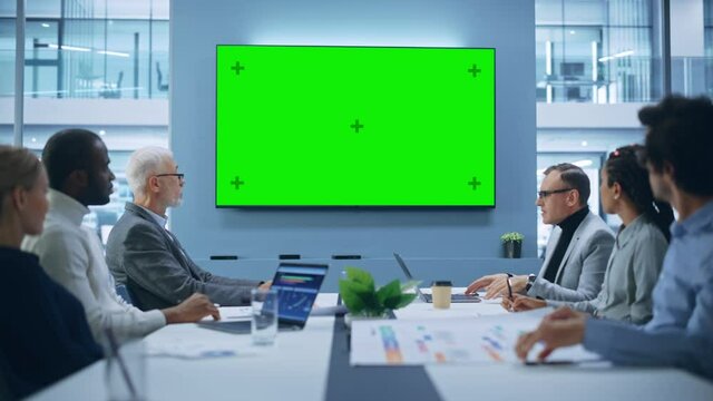 Multi-Ethnic Office Conference Room Meeting: Diverse Team of Successful Managers, Executives Talk, Use Green Screen Chroma Key TV. Group of Businesspeople Work on Strategy for an e-Commerce Startup