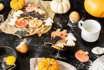 Halloween cookies on the black background with pumpkins, flour, beaten egg, milk