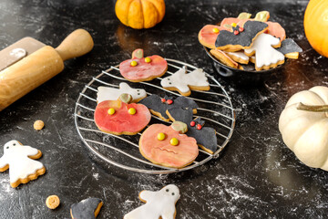 Halloween cookies on the black background with pumpkins and rolling pin