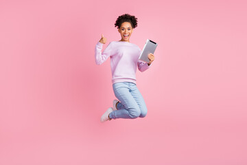 Full size photo of excited cheerful smiling afro girl jumping with tablet show thumb-up isolated on pink color background