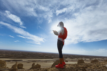 Successful woman hiker use smartphone on the sunset desert