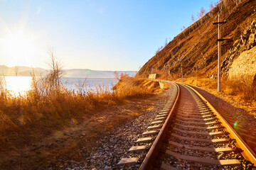 Circum Baikal railway running along the shore of Lake Baikal on an autumn sunny day with a yellow landscape around