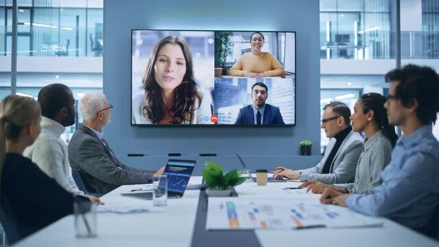 Video Conference Call in Office Boardroom Meeting Room: Executive Directors Talk with Group of Multi-Ethnic Entrepreneurs, Managers, Investors. Businesspeople Discuss e-Commerce Investment Strategy