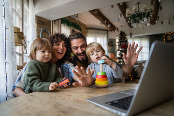 Happy young family making video call with laptop at home