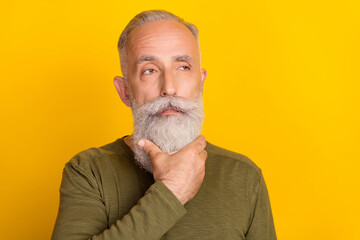 Photo of thoughtful grandpa touch well-groomed beard look empty space wear green shirt isolated yellow color background