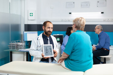 Doctor showing human skeleton image on modern tablet for osteopathy diagnosis. Medic explaining...