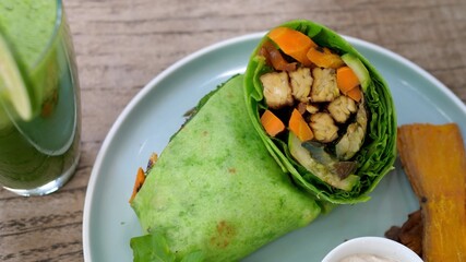 Top view of healthy vegan lunch of plant base green wrap and freshly squeezed vegetable juice.