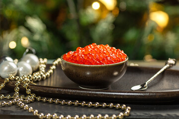 Red caviar in a a ceramic bowl, silver beads and pearls on a silver tray. Christmas and New Year background
