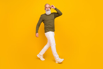 Fototapeta na wymiar Photo of cheerful confident tourist old man walk wear specs green shirt pants footwear isolated yellow color background