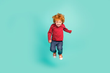 Full size photo of angry small boy jump wear shirt jeans sneakers isolated on blue background