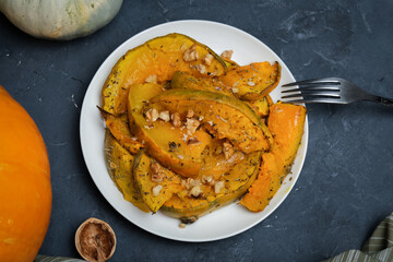 Plate of baked pumpkin sprinkled herbs and walnuts.