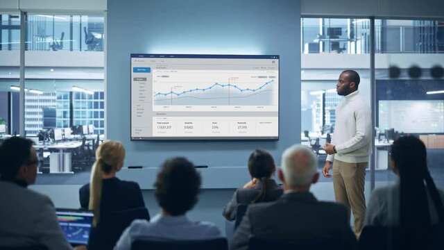 Modern Product Presentation Event: On-Stage Successful Black Businessman Speaker Presents e-Commerce Startup Big Data Statistics, Charts, Revenue Growth Infographics. Live Event. Press Conference