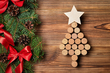 Christmas tree from wine corks with a star on top on a wooden background with fir branches, cones and bows