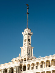 Fototapeta na wymiar Northern River Station. Spire with a star on the roof of the building against the blue sky. Side view. Close-up, vertical.