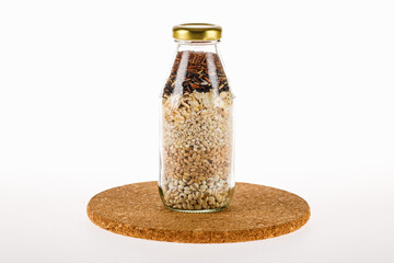 Natural dry organic cereal from brown rice and raw bean grains filled in gorgeous transparent glass bottle for healthy nourishment ingredient of vegan food cooking