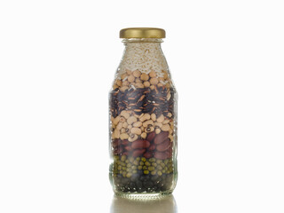 Transparent glass bottle containing natural cereal grain, seed, dry food compound of mixed healthy organic brown rice, soybeans, red beans, white beans, mung beans as ingredient for vegan menu